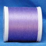 Lavender purple thread on white plastic spool against blue fabric background