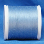 Light blue thread wound on white plastic spool against blue fabric background