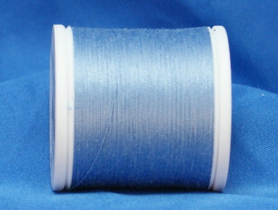 Light blue thread wound on white plastic spool against blue fabric background