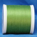 Spring green thread wound on white plastic spool against blue background