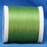 Spring green thread wound on white plastic spool against blue background