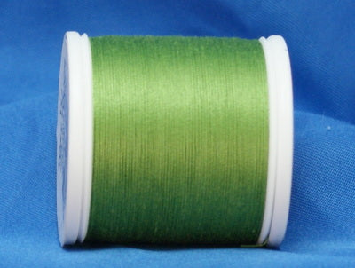 Spring green thread wound on white plastic spool against blue background