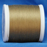 Light brown thread on white plastic spool against blue fabric background