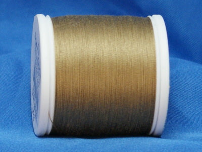 Light brown thread on white plastic spool against blue fabric background
