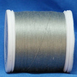 Gray thread wound on white plastic spool against blue background