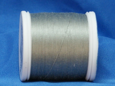 Gray thread wound on white plastic spool against blue background
