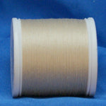 Natural colored thread wound on white plastic spool against blue background