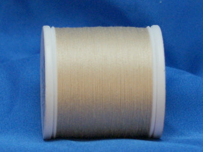 Natural colored thread wound on white plastic spool against blue background