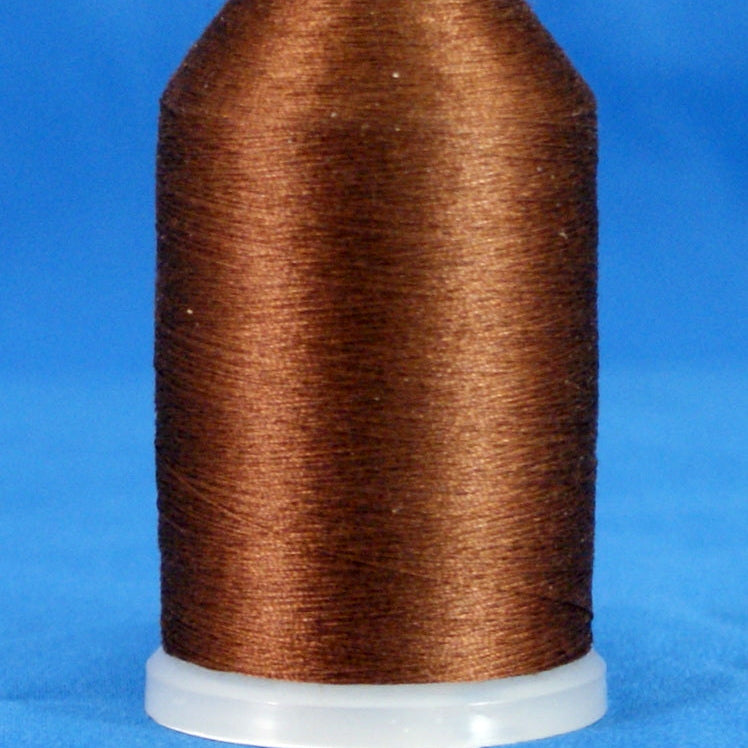 Brown thread wound on white plastic cone with tapered shape against blue background