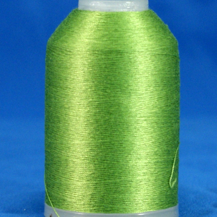 Spring green embroidery thread wound on white plastic cone against blue background
