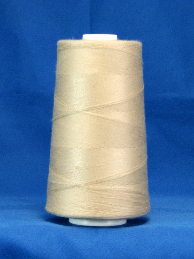 Ecru thread wound on white plastic cone against blue background