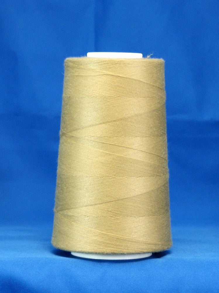 Khaki colored thread wound on white cone spool against blue background