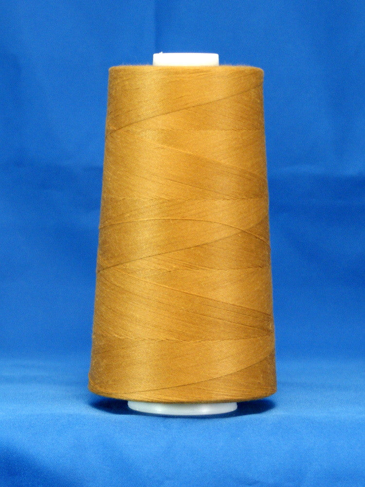 Golden brown thread wound on white plastic cone against blue background