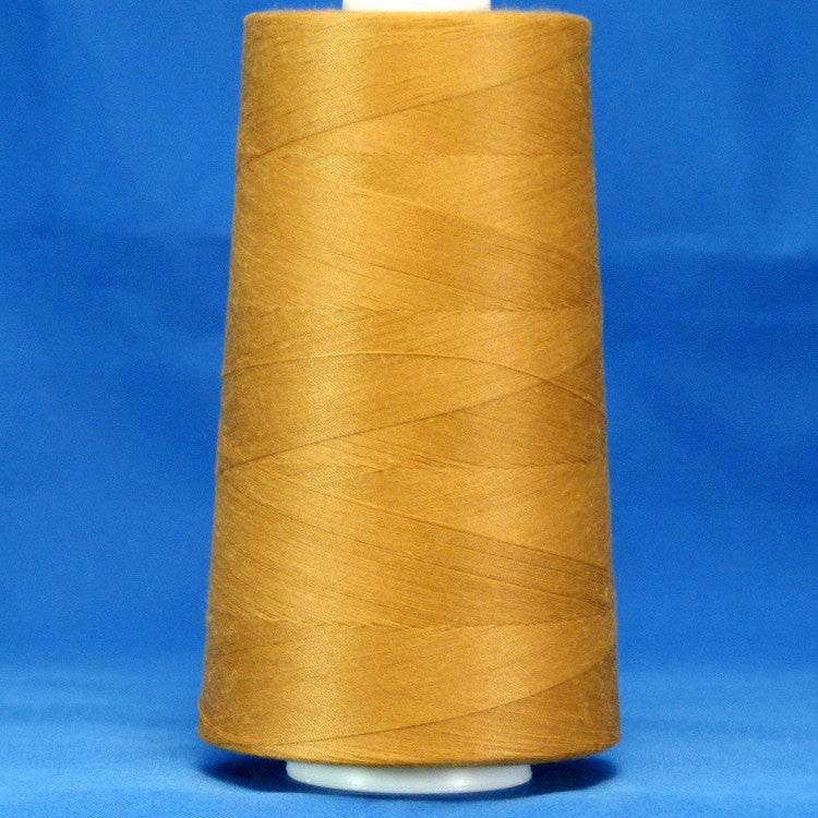 Golden brown thread wound on white plastic cone against blue background