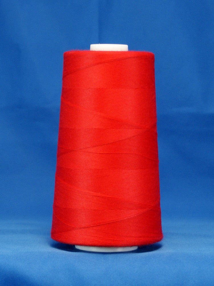 Red thread cone on white spool against blue background, tightly wound scarlet colored thread