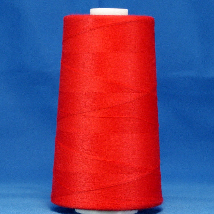 Red thread cone on white spool against blue background, tightly wound scarlet colored thread