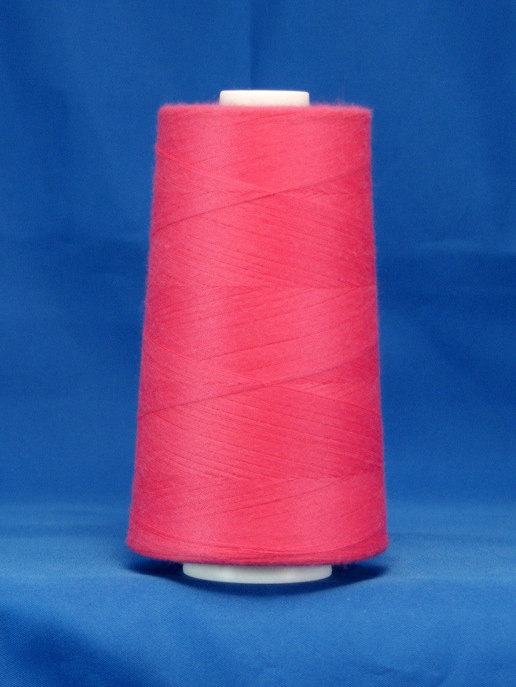 Fuschia pink thread wound on white plastic cone against blue background