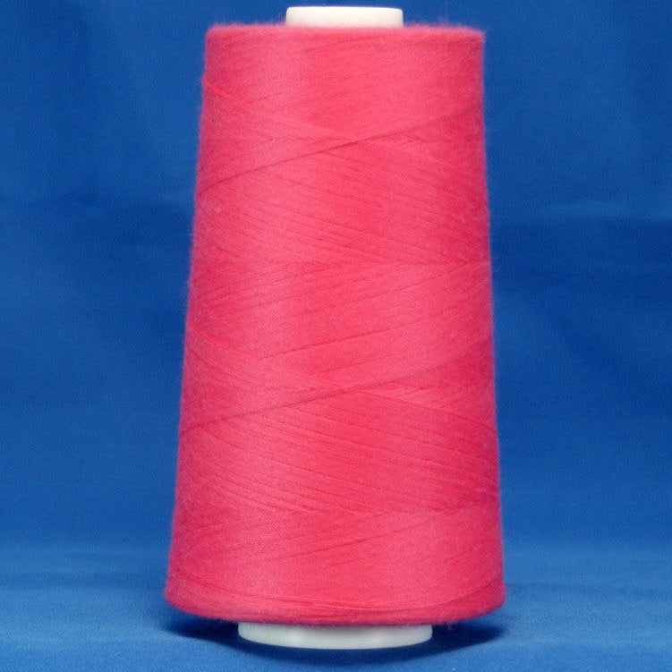 Fuschia pink thread wound on white plastic cone against blue background