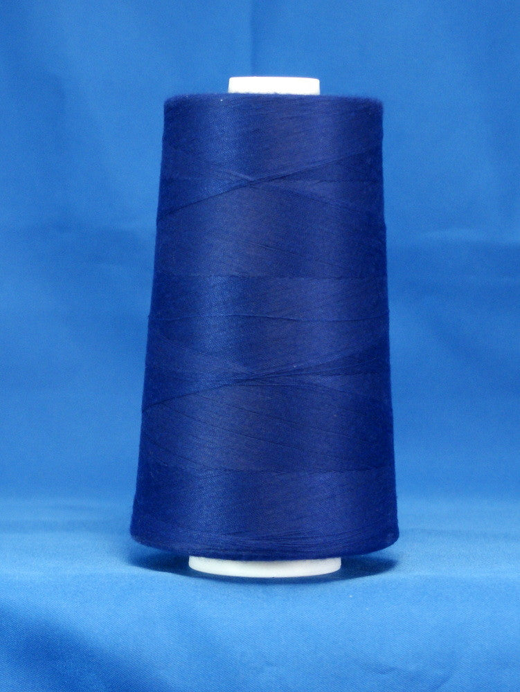 Royal blue thread wound on white plastic cone against blue background