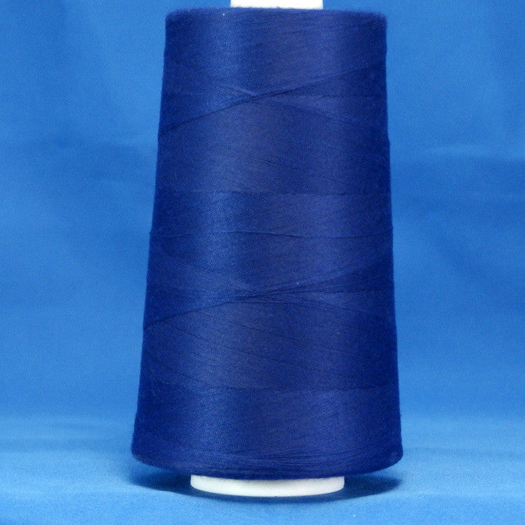 Royal blue thread wound on white plastic cone against blue background