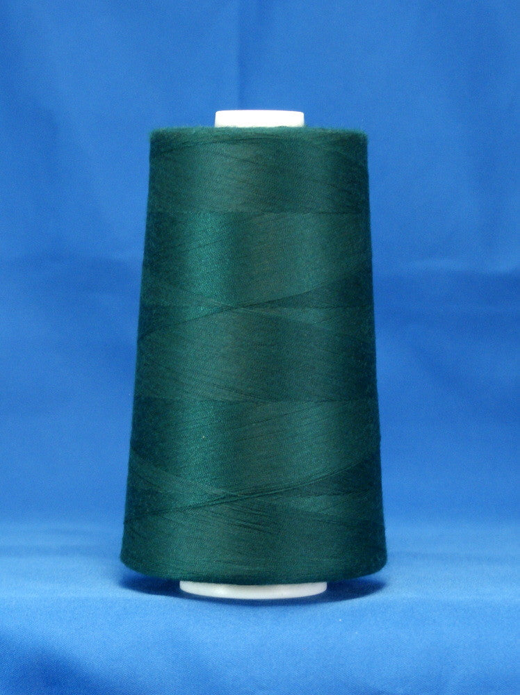 Green thread cone on white spool against blue background, showing wound polyester thread in spruce color