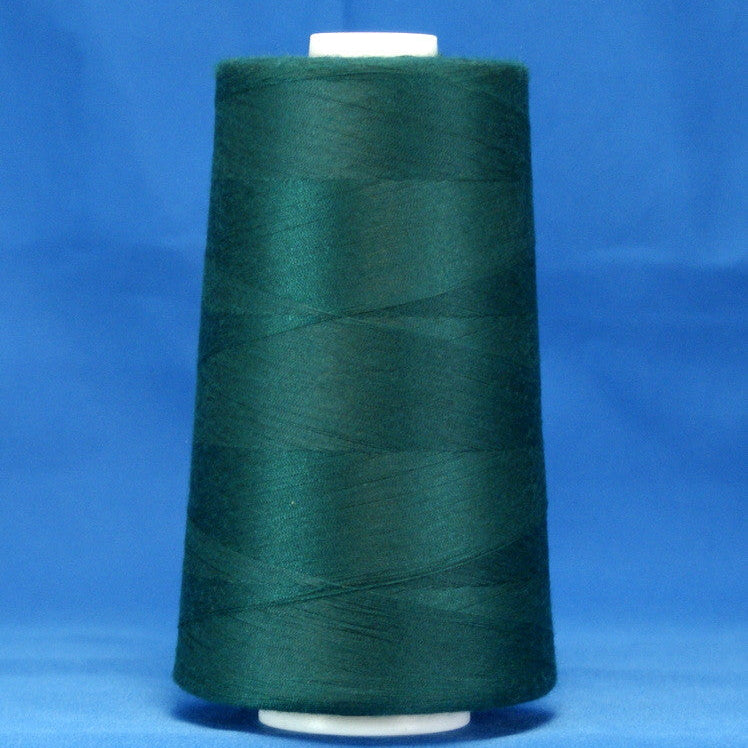 Green thread cone on white spool against blue background, showing wound polyester thread in spruce color