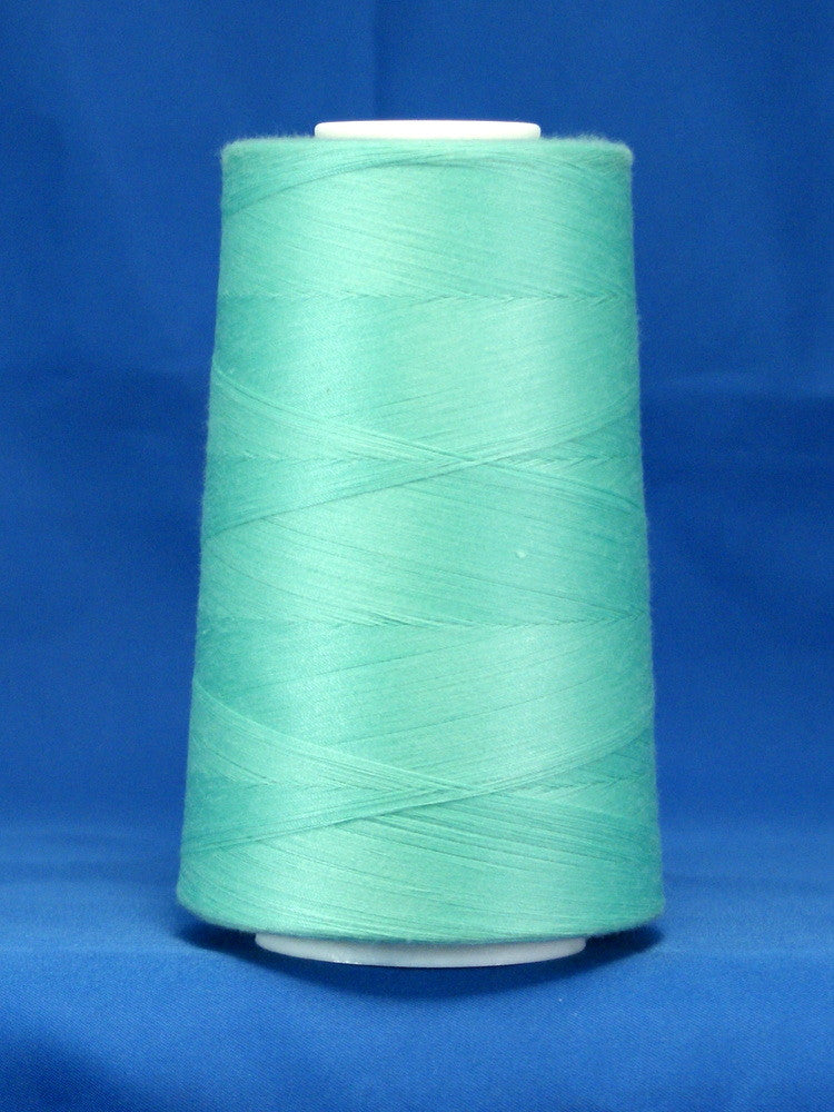 Aqua green thread wound on white plastic cone against blue background