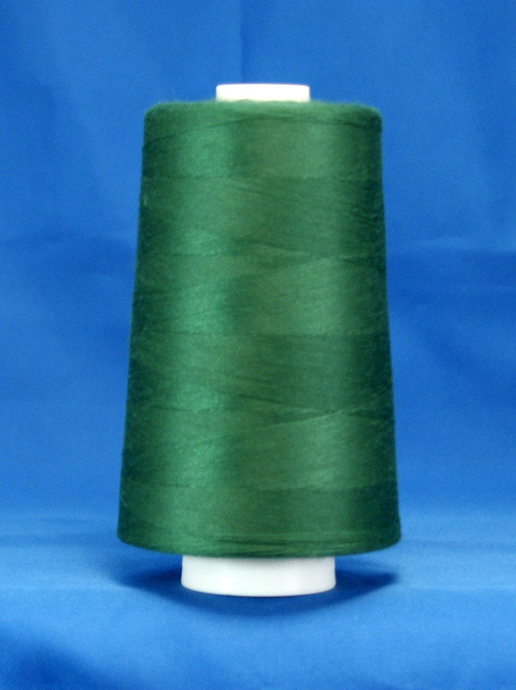 Forest green thread on white cone spool against blue background