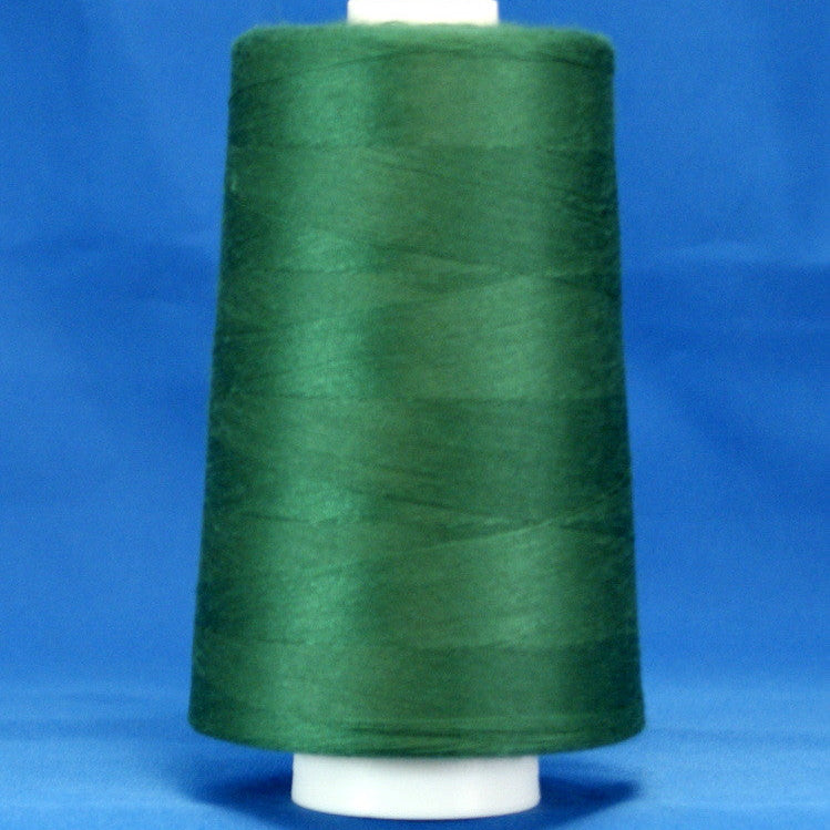Forest green thread on white cone spool against blue background