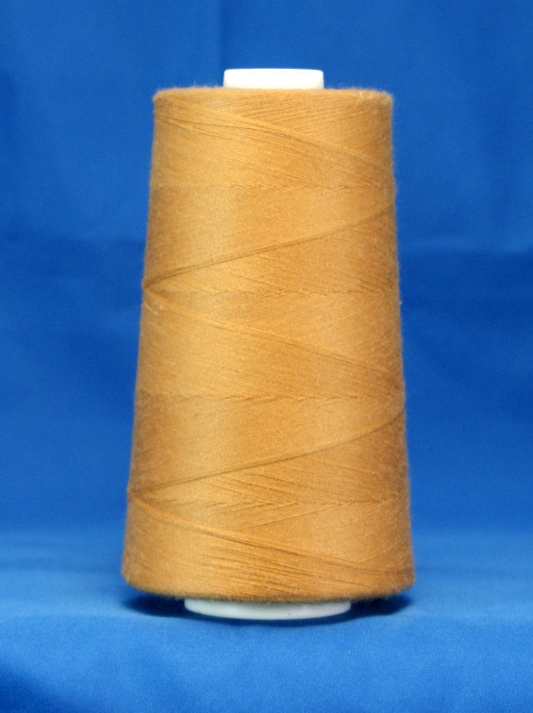Golden yellow thread wound on white plastic cone against blue background