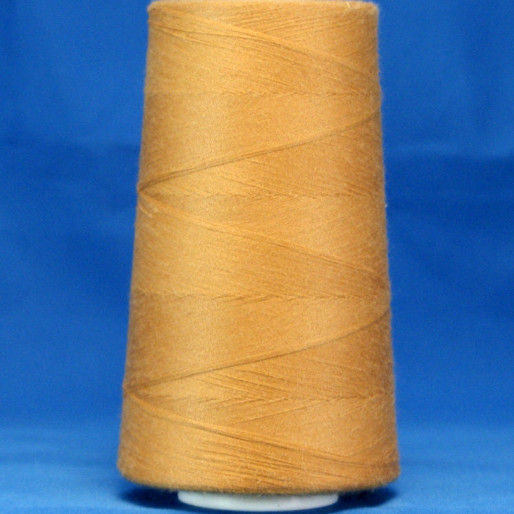 Golden yellow thread wound on white plastic cone against blue background