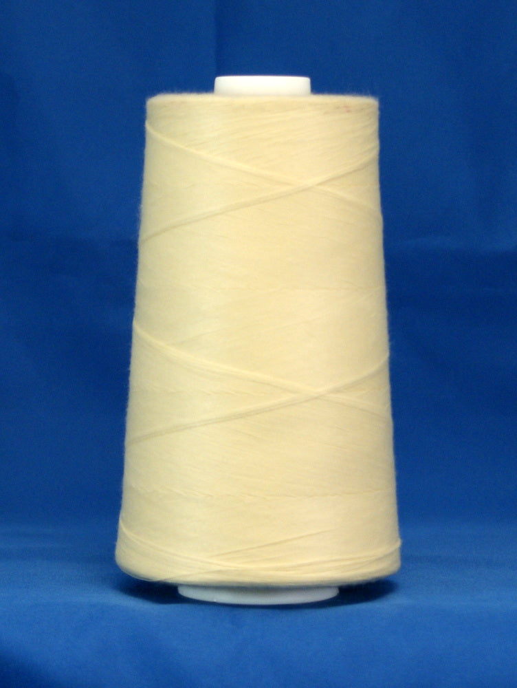 Cream colored thread wound on white plastic cone against blue background