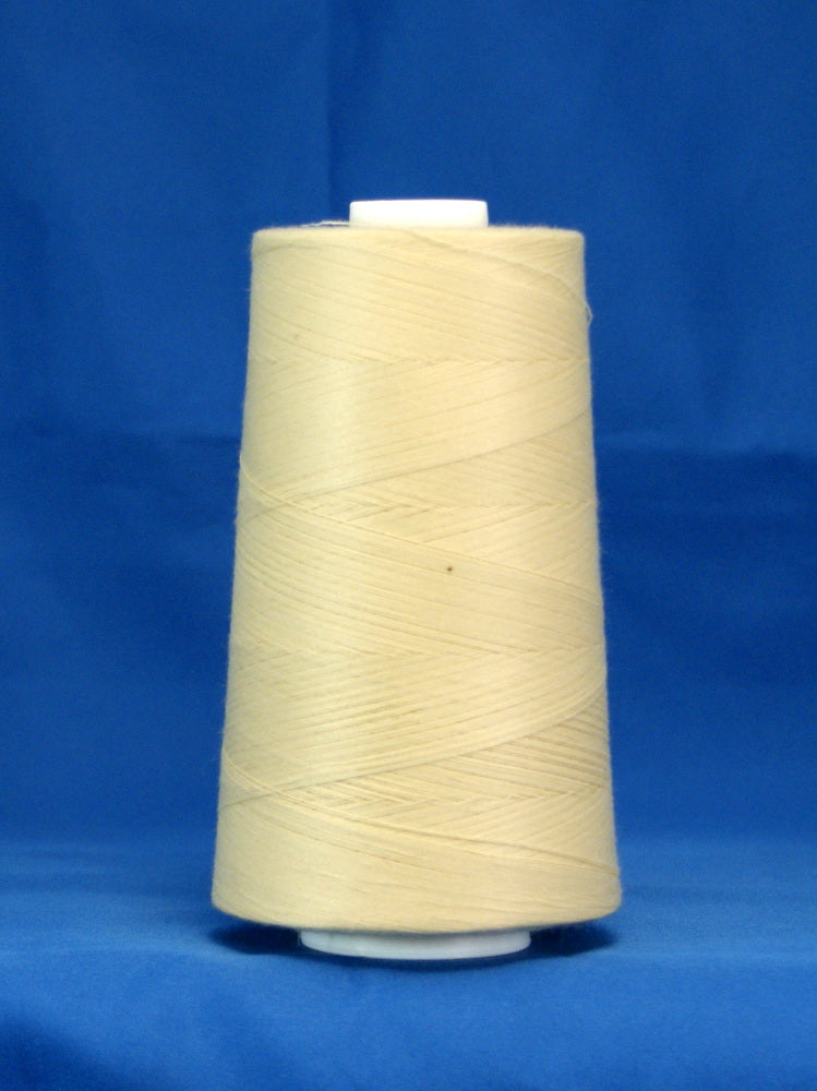 Parchment colored thread wound on white plastic cone against blue background