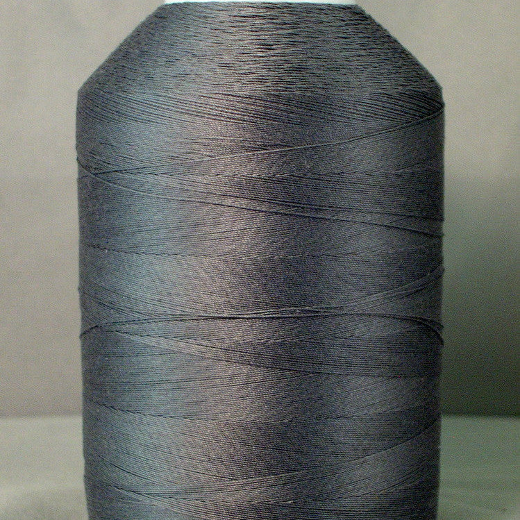 Gray thread cone on white spool for sewing and quilting
