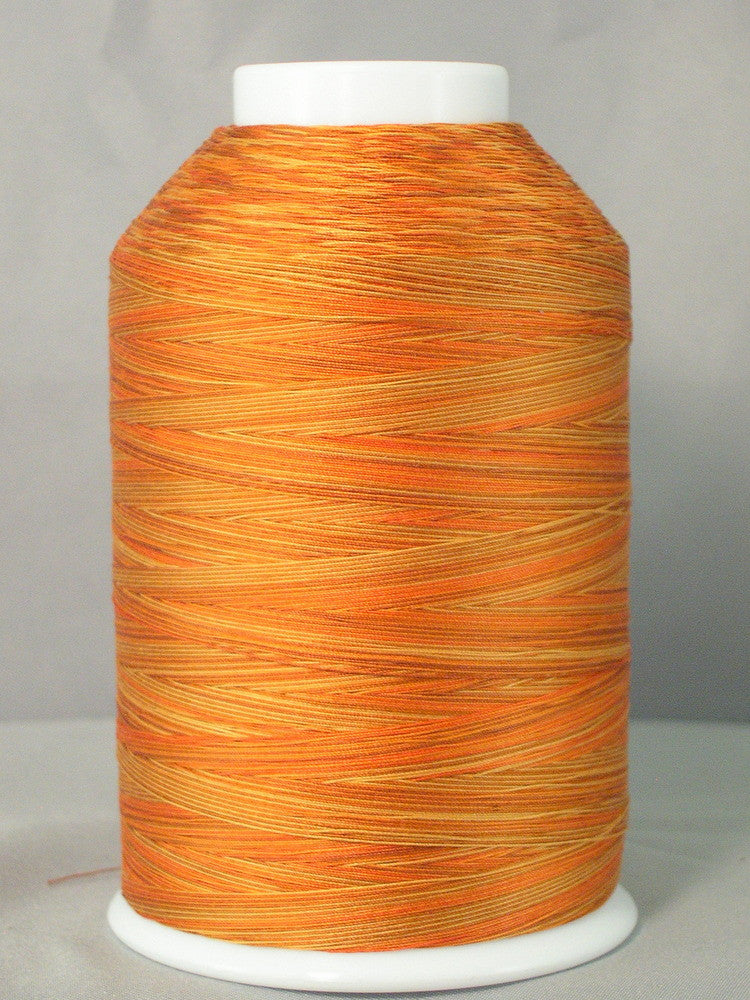 Variegated orange and gold quilting thread wound on white plastic cone