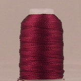 Wine colored rayon thread wound on white mini cone spool against neutral background