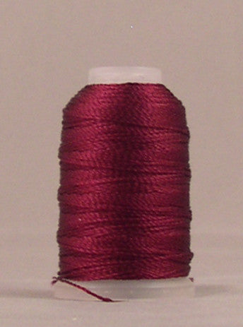 Wine colored rayon thread wound on white mini cone spool against neutral background