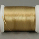 Gold rayon thread on white plastic spool, neatly wound with metallic sheen