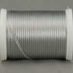 Silver rayon thread wound on white plastic spool with loose thread end visible