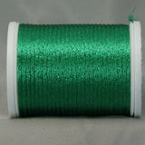 Green metallic rayon thread on white plastic spool, shimmery finish visible on wound thread
