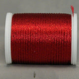 Wine red metallic thread on white plastic spool with loose thread end visible