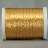 Golden metallic thread on white plastic spool with shimmery copper highlights