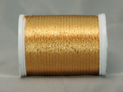 Golden metallic thread on white plastic spool with shimmery copper highlights