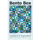 A quilt pattern cover showing a geometric design with interlocking squares in blues, greens, black and white fabrics arranged in a modern bento box style.