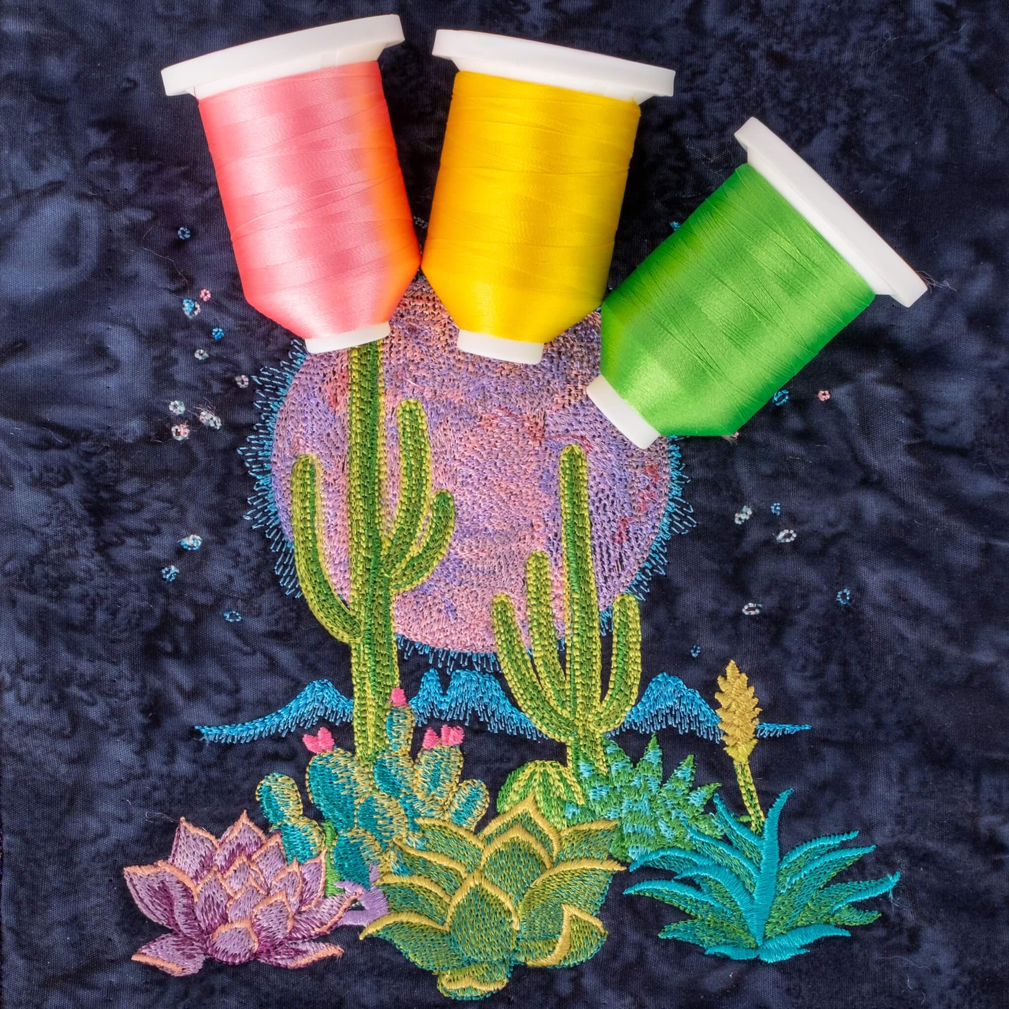 Embroidered artwork of colorful thread spools and cacti on a dark background
