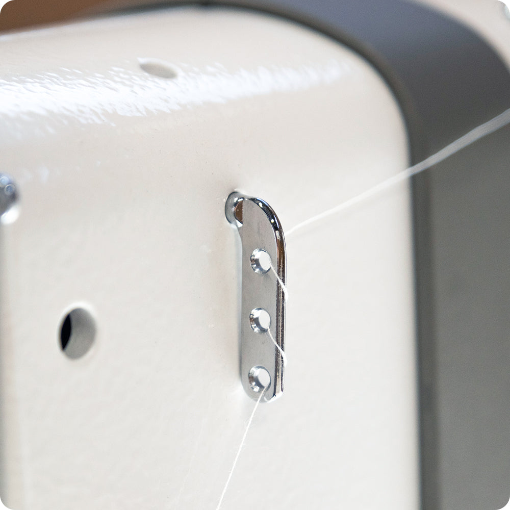 close up image of the three hole tension guide with QuiltMaker white thread