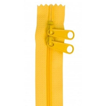 Yellow zipper with two pull tabs and serrated fabric edges at the top