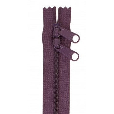 Eggplant purple zipper with two pull tabs and scalloped tape edges on white background.