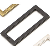 Black metal rectangular ring hardware with flat design, shown alongside gold and white frame corners on white background.