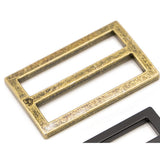 Two metal rectangular sliders in antique brass finish with weathered texture, and a partial view of a black slider in the corner.